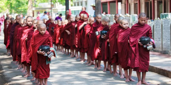 Buddhist novices walk to collect alms and offerings