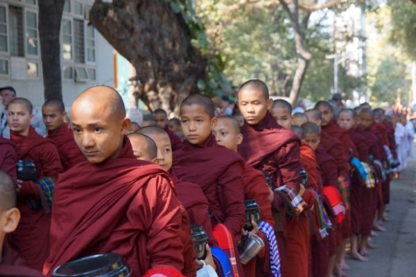 Buddhist novices walk to collect alms and offerings